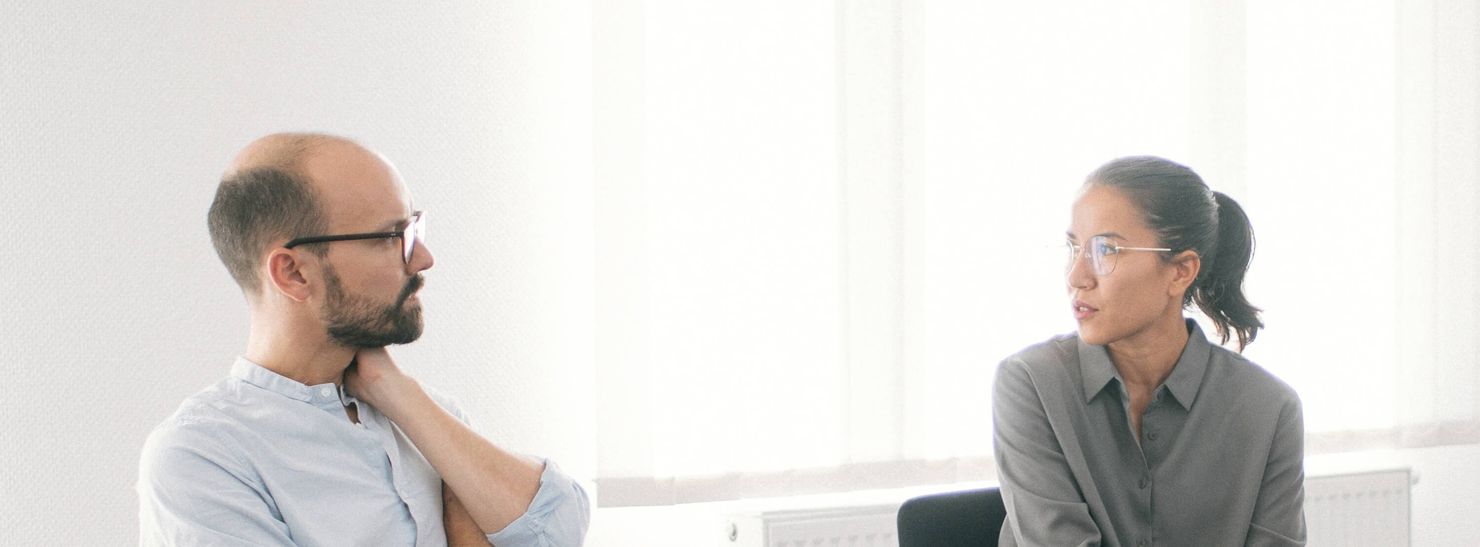 Klinikaufnahme Ein Mann und eine Frau sitzen auf Stühlen und sprechen miteinander.