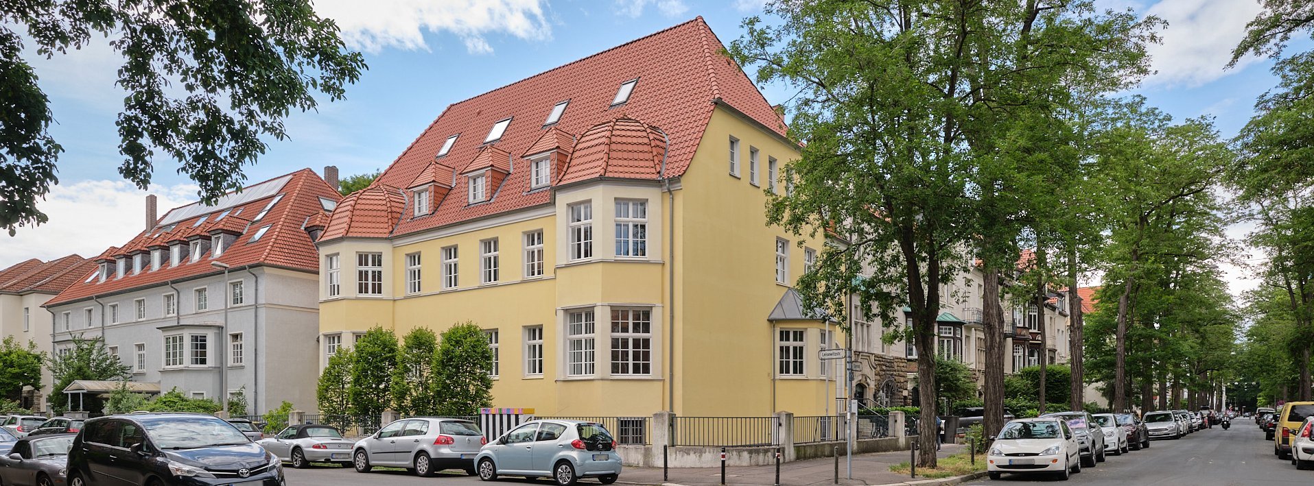 Außenansicht der Oberberg Tagesklinik Hannover, großes gelbes Eckhaus mit rotem Ziegeldach