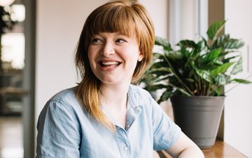 Suchttherapie - Lächelnde Frau im blauen Oberteil mit braunen Haaren