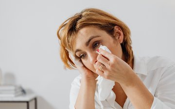 Frau wischt sich mit Taschentuch tränen weg