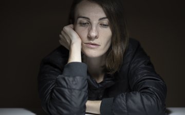 Die Folgen von Covid-19 für die Psyche – Depressionen in der Pandemie Frau in grauem Oberteil guckt traurig