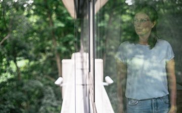 Welche Anzeichen gibt es bei einer Depression? frau vor fenster