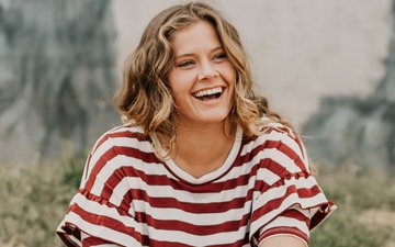 Depression - Eine junge lächelnde Frau in einem rot-weißen Oberteil