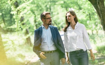 Therapiegespräch zur Behandlung von Somatoformen Störungen In der Natur findet ein Therapiegespräch zur Behandlung Somatoformer Störungen statt, Bäume und grüne Blätter im Hintergrund