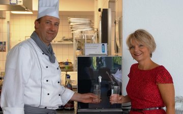 Auf der Höhe der Zeit mit Trinkwasserspendern Artikel Trinkwasserspender: Koch und Frau vor einem Trinkwasserspender