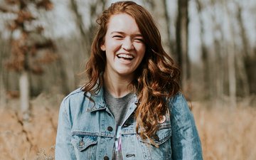 Ernährung - Ein Mädchen im Wald mit rot-braunen Haaren lacht in die Kamera