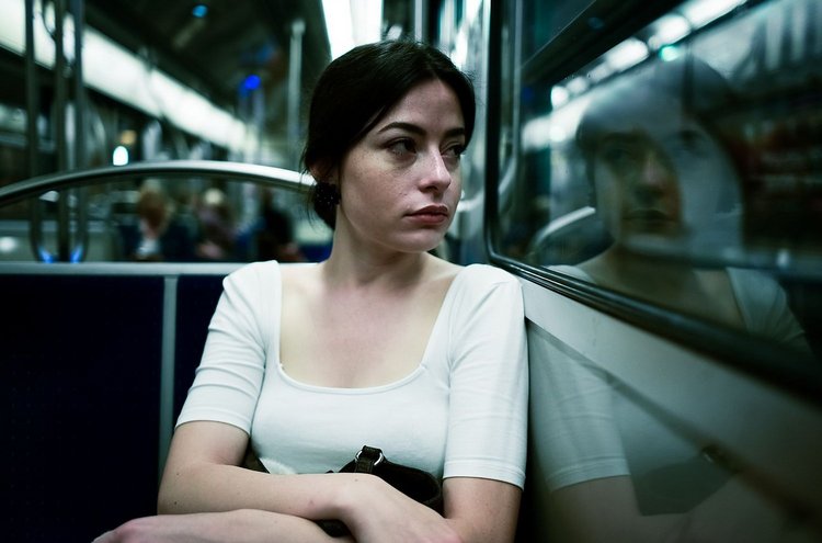 Frau sitzt im Bus und schaut aus dem Fenster, düstere Atmosphäre