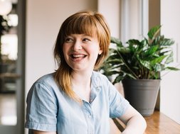 Suchttherapie - Lächelnde Frau im blauen Oberteil mit braunen Haaren