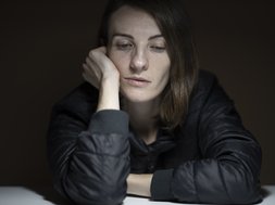 Die Folgen von Covid-19 für die Psyche – Depressionen in der Pandemie Frau in grauem Oberteil guckt traurig