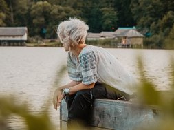 Depression: Eine Frau mit weißen Haaren sitzt am Wasser