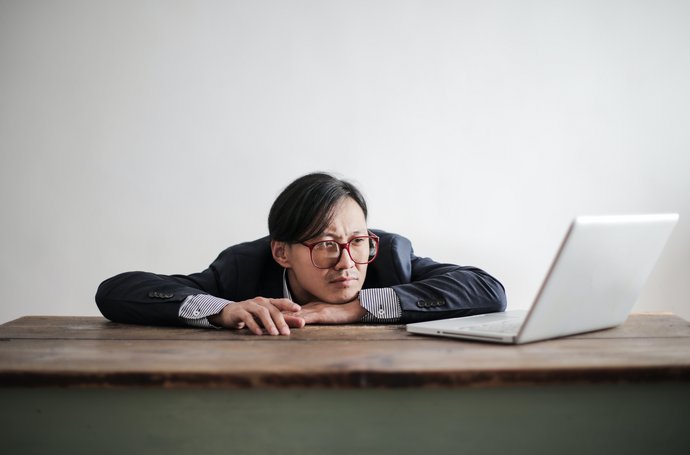 Mann langweilt sich vor Laptop