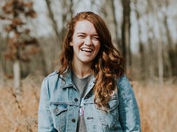 Ernährung - Ein Mädchen im Wald mit rot-braunen Haaren lacht in die Kamera