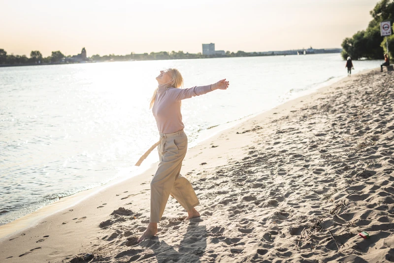 Weit aufnahme von einer Frau am strand mit offenen armen
