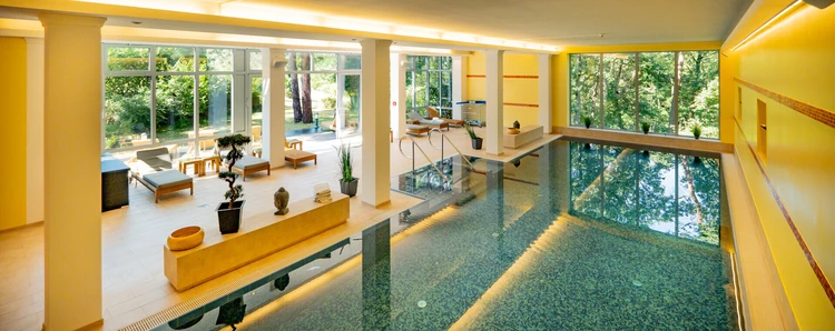 Innenpool der Oberberg Fachklinik Potsdam mit Liegen und gro&szlig;en Fenstern zum Wald