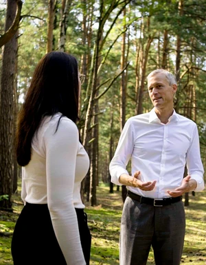 Frau und Mann stehen im Gespr&auml;ch in einem Waldst&uuml;ck