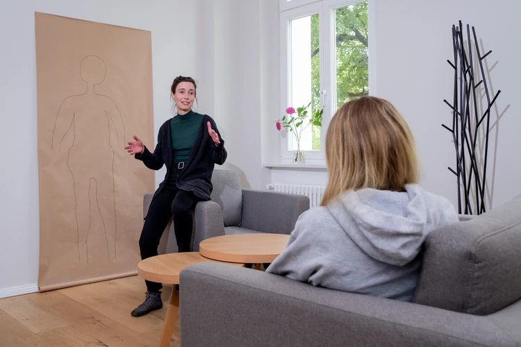 Frau spricht mit einer Person in einem hellen Raum