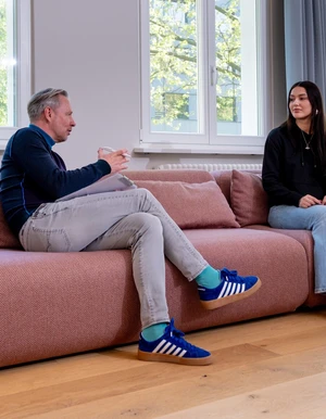 Zwei Personen sitzen in einem Gespr&auml;ch auf einem Sofa