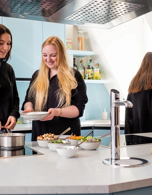 Mehrere Personen bereiten in einer K&uuml;che gemeinsam Essen zu