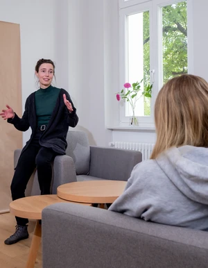 Frau spricht mit einer Person in einem hellen Raum