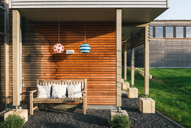 &Uuml;berdachter Sitzplatz vor einer Holzfassade