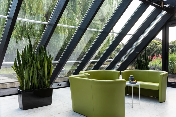 Sitzbereich mit gr&uuml;nen Sofas und Glasdach