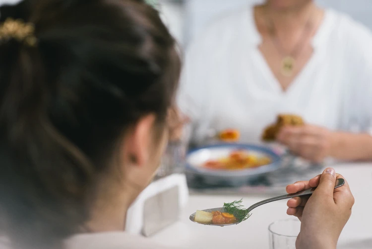 Personen sitzen gemeinsam beim Essen am Tisch