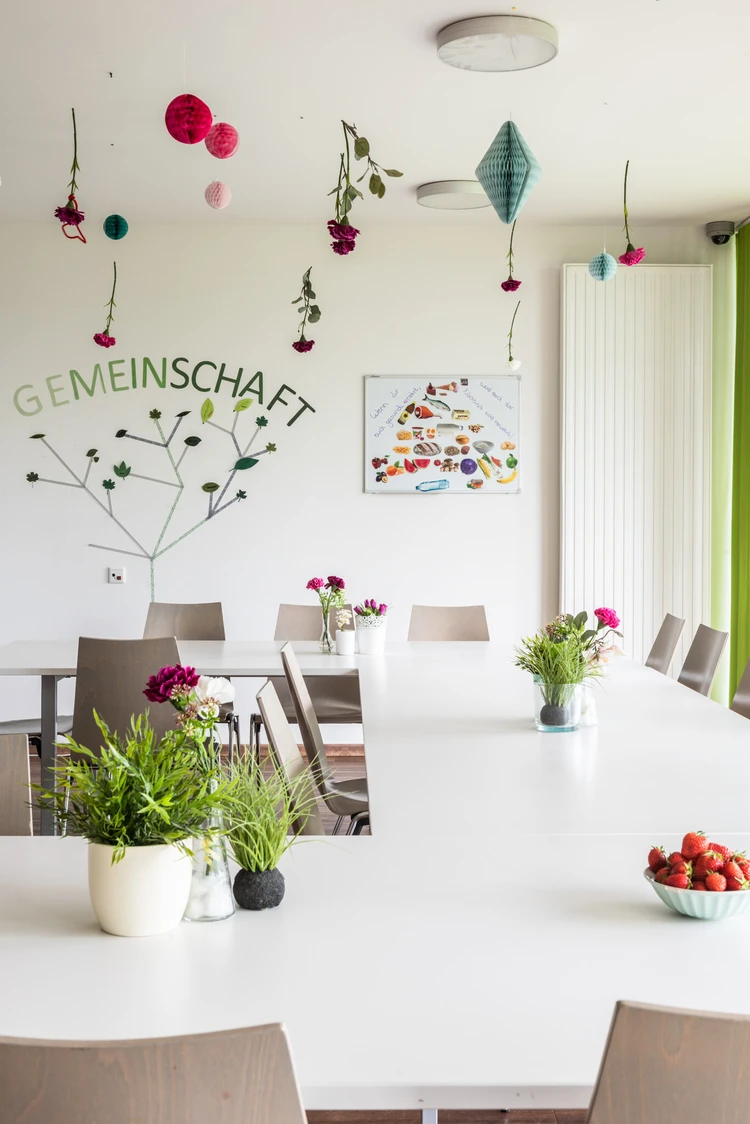 Heller Raum mit bunter Wandgestaltung und Blumen auf den Tischen