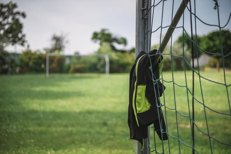 Sportjacke h&auml;ngt an einem Fu&szlig;balltor im Gr&uuml;nen