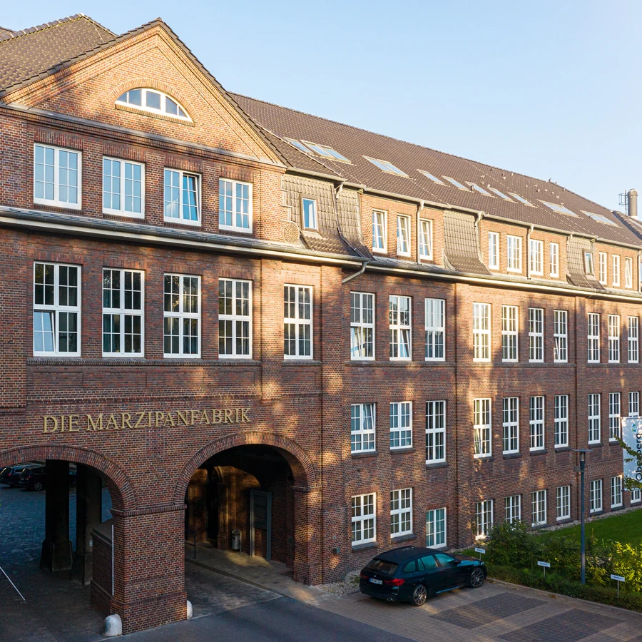 Historisches Backsteingeb&auml;ude der Oberberg Fachklinik Marzipanfabrik mit Torbogen und Innenhofzufahrt bei Tageslicht.