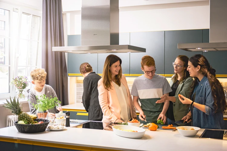 Mehrere Personen bereiten gemeinsam Essen in einer K&uuml;che zu