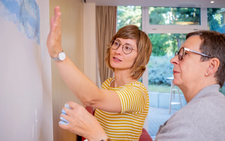 zwei Personen betrachten gemeinsam ein Bild an der Wand