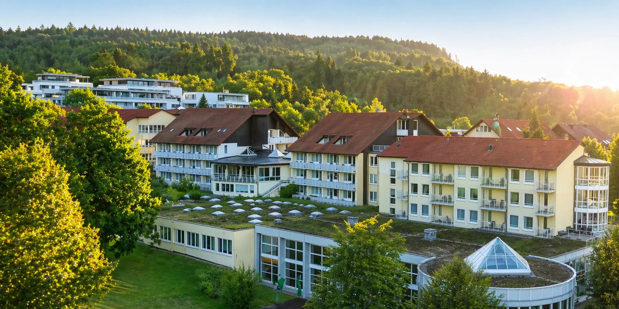 Geb&auml;ude der Oberberg Fachklinik Rhein-Jura vor bewaldetem Hang im Abendlicht