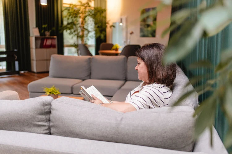 Person sitzt lesend auf einem Sofa in einem Aufenthaltsraum