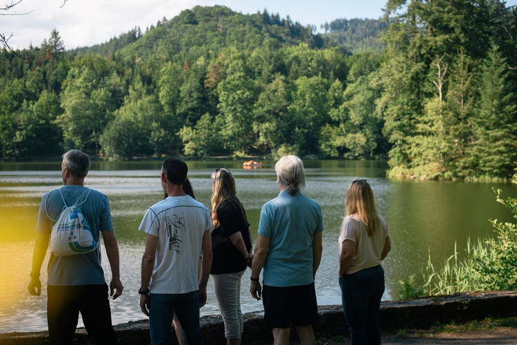 Gruppe steht am Seeufer mit Blick auf die Landschaft