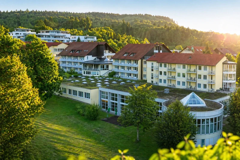 Geb&auml;ude der Oberberg Fachklinik Rhein-Jura vor bewaldetem Hang im Abendlicht