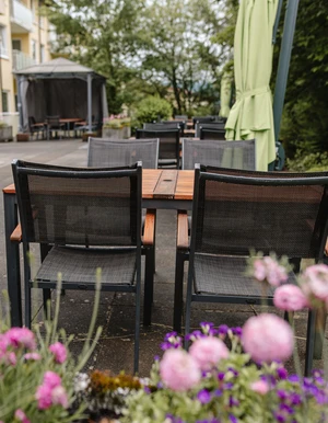 Terrasse mit Tischen und Sonnenschirmen in einer gr&uuml;nen Au&szlig;enanlage