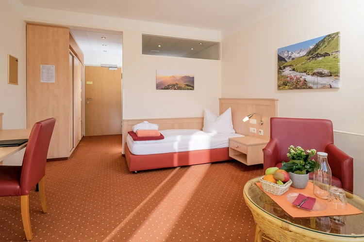 Patientenzimmer mit Bett, Sessel und gro&szlig;em Fenster