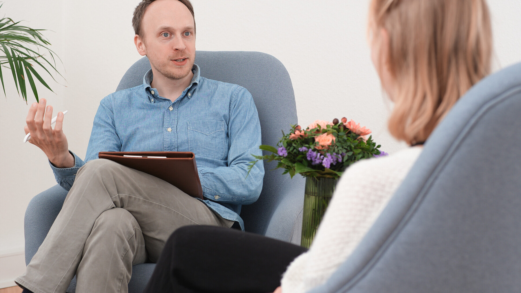 Mann mit Klemmbrett sitzt einer Frau in einem Beratungsgespr&auml;ch gegen&uuml;ber