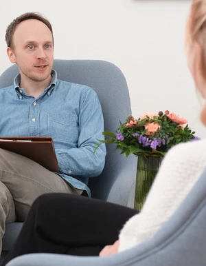 Mann mit Klemmbrett sitzt einer Frau in einem Beratungsgespr&auml;ch gegen&uuml;ber