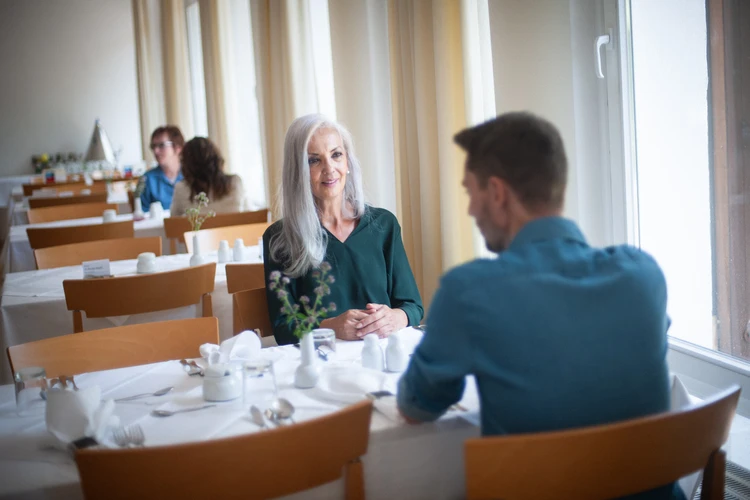 Personen sitzen an einem gedeckten Tisch in einem hellen Raum