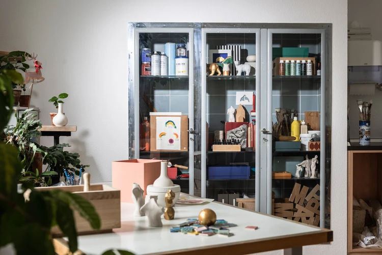 Schrank mit Farben, Pinseln und Werkmaterialien in einem hellen Atelierraum