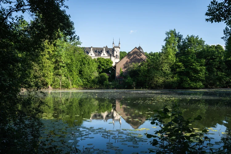 Blick &uuml;ber einen See auf das Wasserschl&ouml;sschen im Gr&uuml;nen