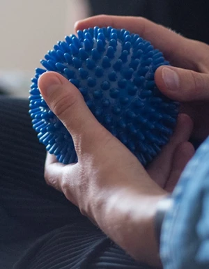 Person h&auml;lt einen blauen Igelball w&auml;hrend eines Gespr&auml;chs