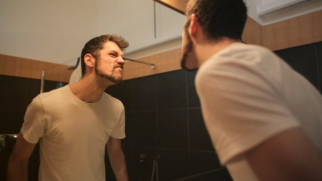 Mann blickt mit angespannter Mimik in den Badezimmerspiegel
