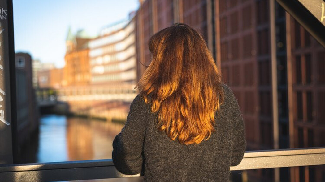 Frau steht auf einer Br&uuml;cke und schaut auf einen Kanal zwischen Backsteingeb&auml;uden