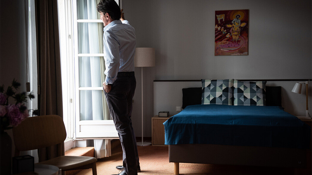 Mann steht nachdenklich am Fenster in einem Zimmer