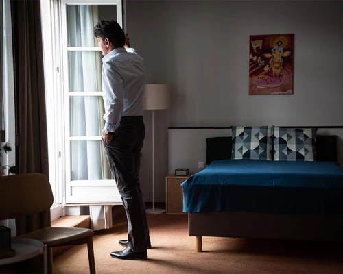 Mann steht nachdenklich am Fenster in einem Zimmer