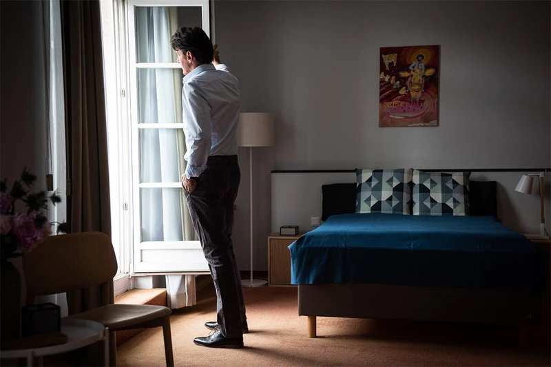 Mann steht nachdenklich am Fenster in einem Zimmer